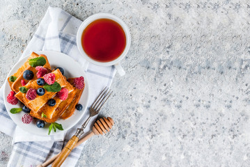 Healthy summer breakfast, baked french toasted bread sticks with fresh berry and honey, morning...