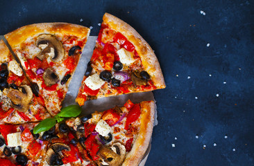 Homemade pizza with tomatoes, mozzarella and basil. Top view with copy space on dark stone table.
