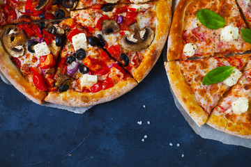 Homemade pizza with tomatoes, mozzarella and basil. Top view with copy space on dark stone table.