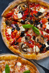 Homemade pizza with tomatoes, mozzarella and basil. Top view with copy space on dark stone table.
