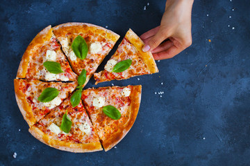Homemade pizza with tomatoes, mozzarella and basil. Top view with copy space on dark stone table.