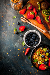 Healthy breakfast with muesli or granola with nuts and fresh berries and fruits - strawberry, blueberry, kiwi, on dark blue table, copy space top view