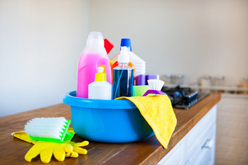 Basket with cleaning items on blurry background white citchen. Cleaning concept.