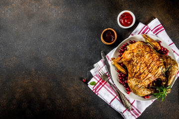 Christmas, thanksgiving food, baked roasted chicken with cranberry and herbs, served with fried vegetables and sauces on dark rusty table, copy space top view