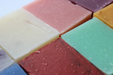 Many small multi-colored pieces of handmade soap on white background