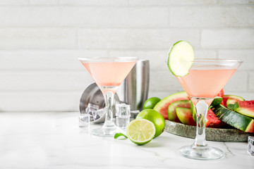 Alcoholic summer beverage, watermelon martini cocktail, with fresh lime and mint, white marble background copy space