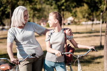 Glad to see you. Charming girl expressing positivity and turning head while looking at her mom