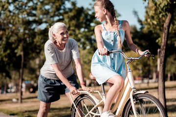 Supporting you. Smiling woman expressing positivity and standing behind bicycle while looking at...