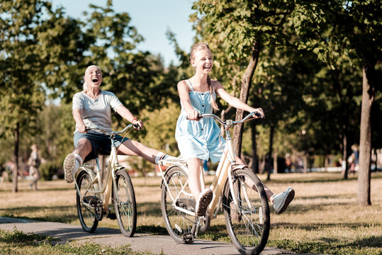 Joyful mood. Happy female person expressing her emotions and holding hands on the handle bar while walking in park
