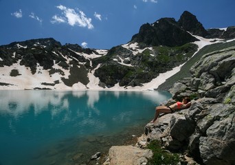 A young woman sunbathes on the shore of a mountain lake, Arkhyz