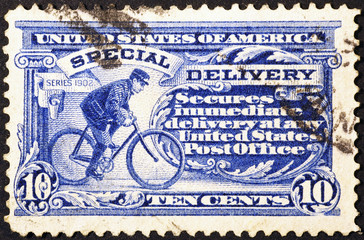 Postman cycling on very old american postage stamp