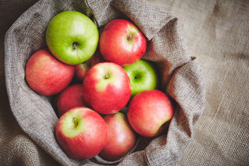 Top view red apples, green apples in basket cover with brown cloth background texture
