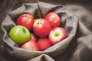 Harvest time, organics apples from nature in basket on sackcloth background texture