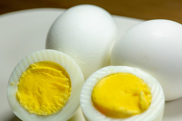 Hardboiled eggs with one cut in half on a plate at the kitchen table