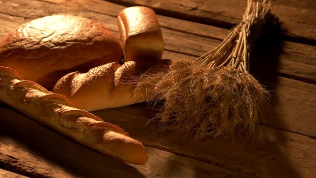 Homemade bread on rustic wooden background. Fresh bread, baguettes and bundle of wheat ears on rustic wooden table. Wheat bread diet.