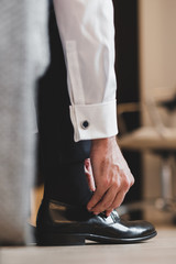 Detail of groom getting ready for wedding ceremony, putting shoes on
