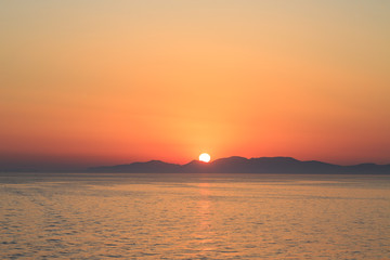 Sunset over island on aegean sea