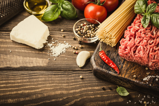 Healthy food background with ingredients for spaghetti Bolognaise or Bolognese with savory minced beef and tomato, basil and spices. Copy space. Retro style toned.