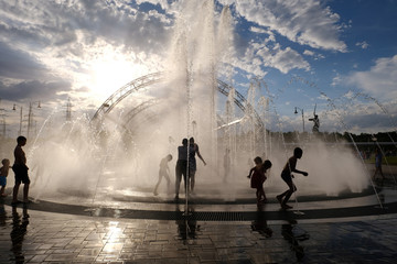 Children frolicking in the fountain in the summer, the heat.