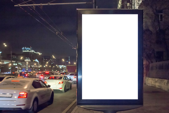 Mock up of blank white vertical light box in a city near traffic jam at night
