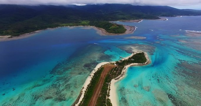 High aerial backwards track revealing beautiful crystal clear turquoise blue water and Mystery Island Vanuatu. Cruise ship tender boat can be seen delivering passengers to this breathtaking island.