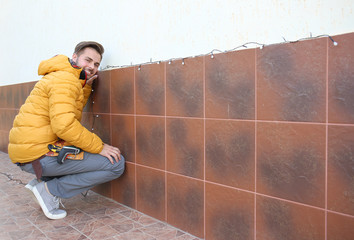 Young man decorating outdoor wall with Christmas lights