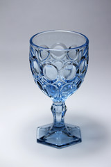 Closeup image of an elegant blue crystal glass goblet with scallop designs and light background