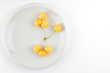 Yellow cherries on white plate, fresh cherries on white background, yellow berries in minimalism style, vegetarian food, isolated