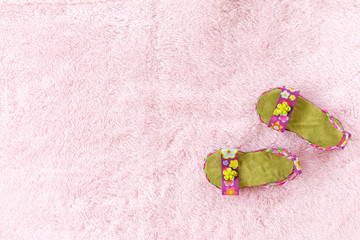 Pair of baby sandals against pink background.