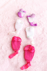 Three pairs of baby sandals against a pink background.