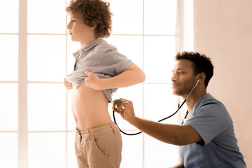 Stop breathing. Serious boy standing in semi position and looking forward while holding his T-shirt © zinkevych