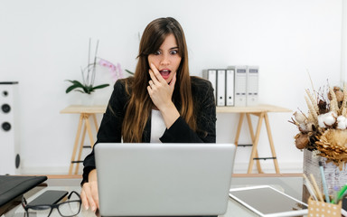 Business woman with surprised expression in her office