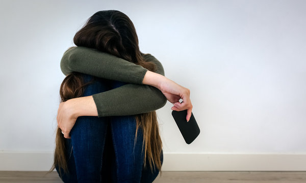 Devastated young woman holding a phone