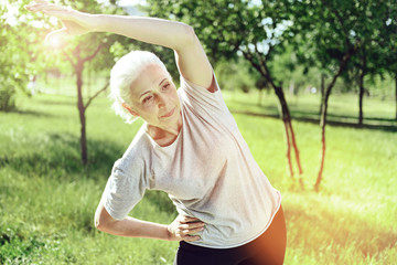 Concentration. Peaceful calm energetic pensioner spending her day in a park and doing useful exercises