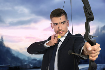 Young businessman practicing archery on white background