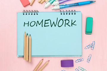 Flat lay composition of school supplies and notebook with word HOMEWORK on wooden background