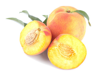 Large fresh peach with green leaf and peach halves on white isolated background.