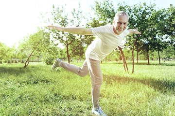 Funny exercise. Positive happy active pensioner enjoying funny morning exercises while spending...