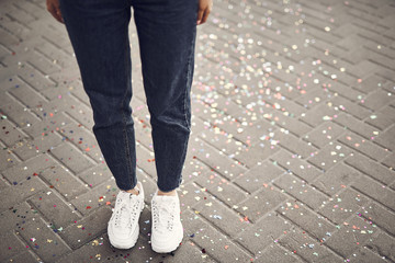 Close up girl legs wearing modern jeans and white trainers standing on bars with spangles outdoor