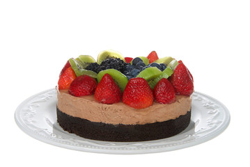 Chocolate cake with Chocolate mousse topped with fresh glazed strawberries, kiwi, blueberries and boysenberries on a porcelain off white plate isolated on white background.