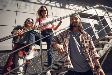 Low angle portrait of beaming lady and outgoing man standing on ladder opposite satisfied guy outdoor. They looking at camera