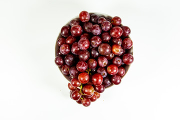 Red seedless grapes in a deep white bowl on a white tale waiting to be eaten