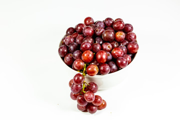 Red seedless grapes in a deep white bowl on a white tale waiting to be eaten