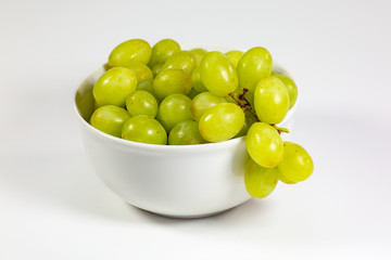 Green seedless grapes in a deep white bowl on a white tale waiting to be eaten