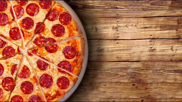 A video of the background pepperoni pizza on a wooden table. Footage.