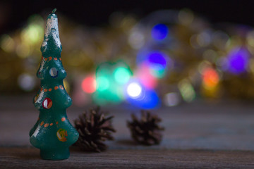 toy Christmas tree-candle on the background of blurred Christmas lights