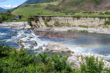 Fototapeta na wymiar Maruia Falls near Murchison, Tasman, New Zealand. The picture is taken on a sunny day with a rainbow formed in the spray. 