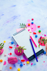 Colorful notebook with pencils and confetti on a light background with copy space. Pink and purple palette still life. Easy lifestyle concept