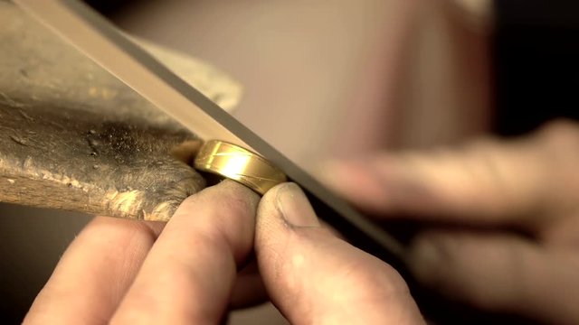 Goldsmith grinding a gold ring.
