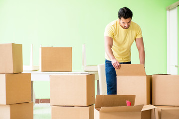 Young handsome man moving in to new house with boxes